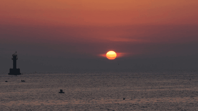 Sunset over the ocean with a lighthouse