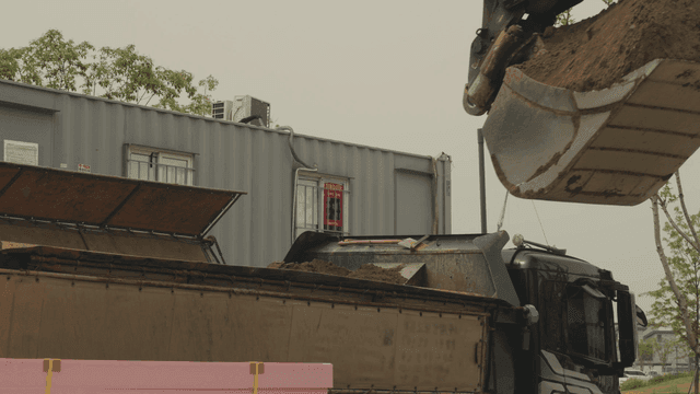 굴착기가 트럭에 흙을 싣는 장면