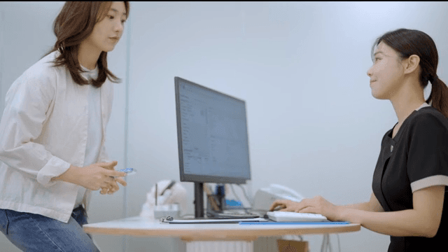 책상 앞에 앉아 환자를 맞이하는 상담실장