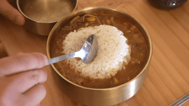 Mixing rice into Korean beef soup by spoon