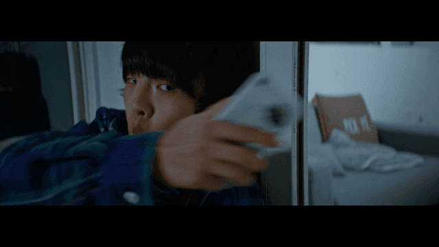 Young nervous man secretly filming with a phone over a wall