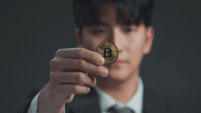 A man holding a Bitcoin coin