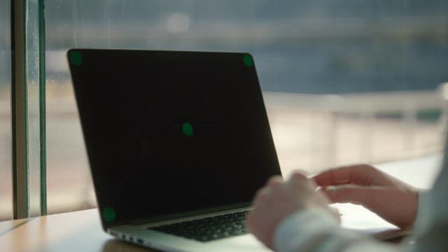 Person typing on a laptop by the window