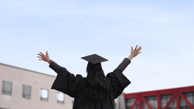 Graduates celebrating graduation with arms outstretched