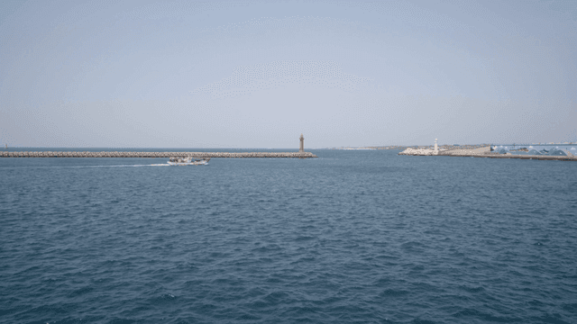 Boat sailing near a red lighthouse