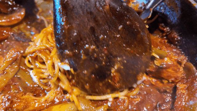 Noodles stir-fried in sauce topped with cheese