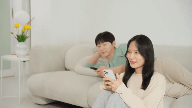 소파에 앉아 스마트폰하는 여자와 텔레비전을 보는 남자