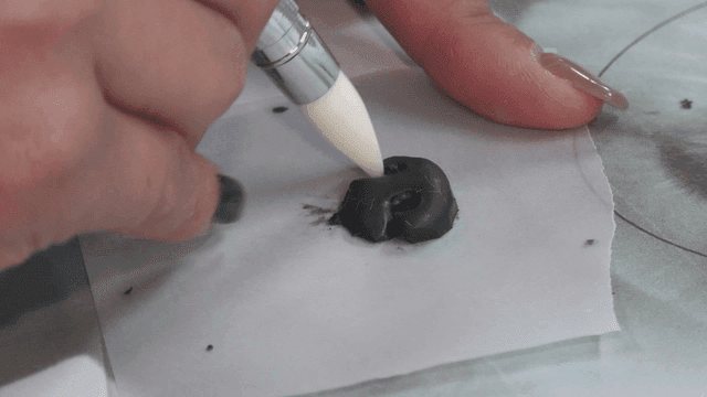 Hands making dog nose model on paper template with tool