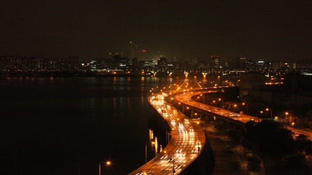 Night View of the City and Bridge Illuminated by Car Lights