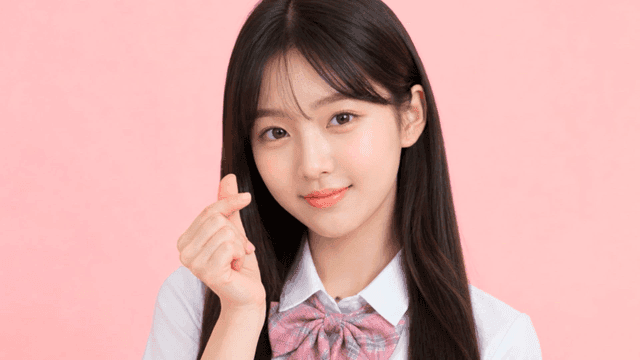 Female student making finger heart while looking straight ahead
