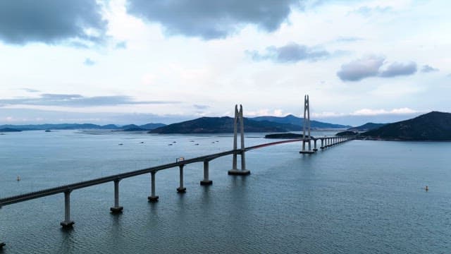 Long bridge over a calm sea with mountains