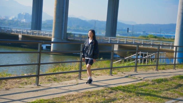 Woman walking by a riverside under a bridge