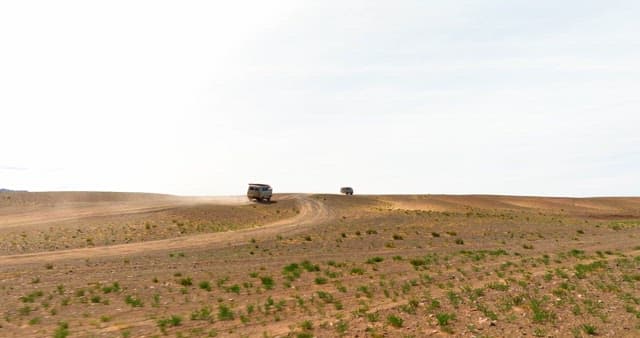 Vans driving through a barren desert landscape