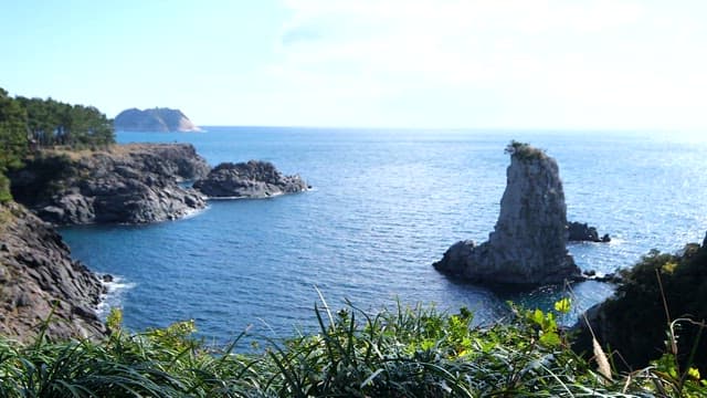 높은 바위가 보이는 화창한 하늘 아래 바다