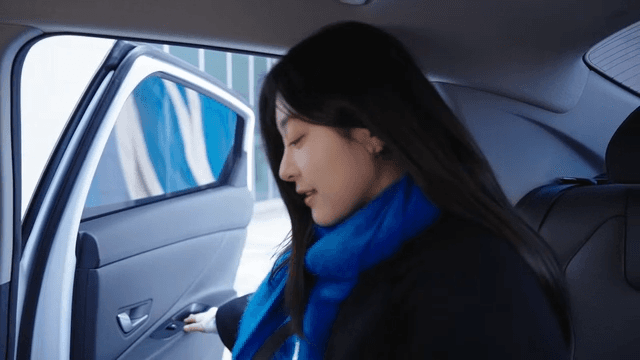 Woman wearing a blue scarf gets into a taxi.