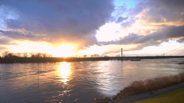 일몰 하늘 아래 고요한 강 위를 지나가는 배