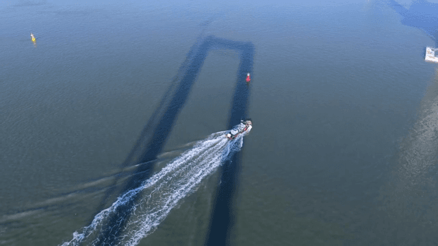 고요한 바다 위 다리 아래를 항해하는 배