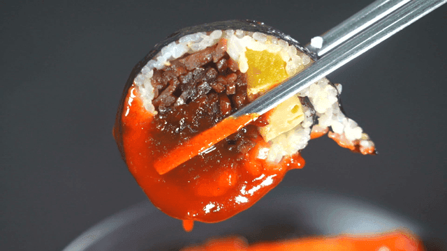 Kimbap dipped in spicy tteokbokki sauce