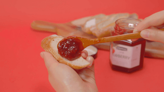 Spreading strawberry jam on a slice of bread