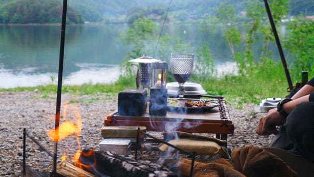 Enjoying a glass of wine at a lakeside campsite with a campfire