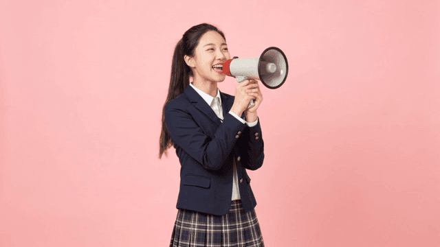 Female student laughing while holding megaphone
