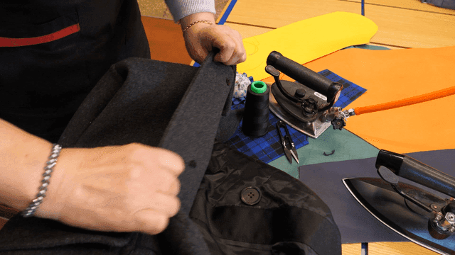 Person sewing a coat with tools nearby
