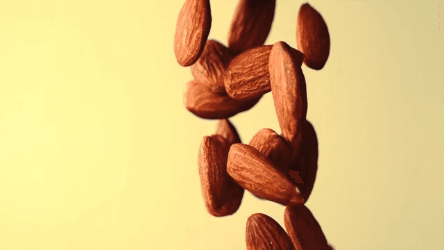 Almonds falling in slow motion against a yellow background