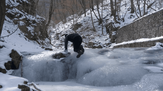 겨울에 얼어붙은 개울가를 걷는 사람