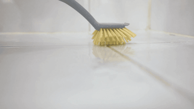 Cleaning a tiled floor with a brush