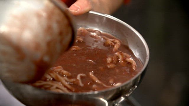 Pouring red bean porridge into a bowl with noodles