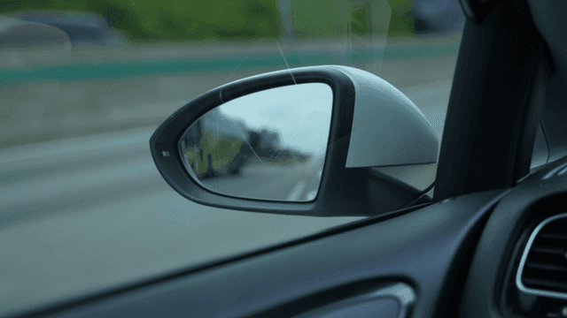 Side mirror of car driving on road