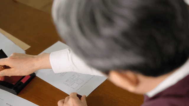 책상 위 서류를 읽고 도장을 찍는 남성