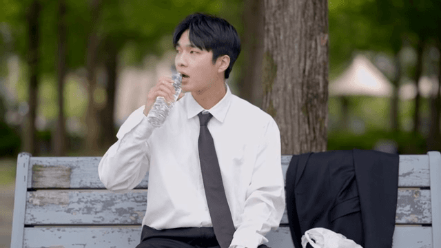 Office worker taking a break while drinking water on a park bench