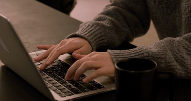 Person Typing on Laptop in Cozy Environment