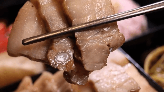 Chopsticks holding slices of bossam