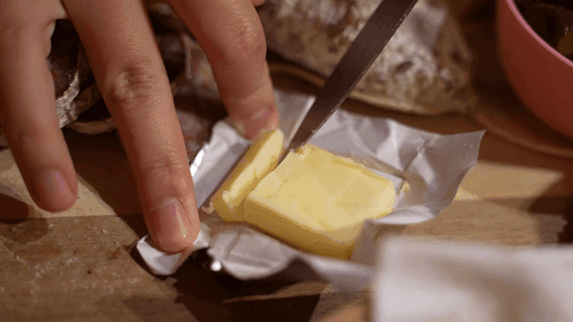 Butter being sliced on a wooden board