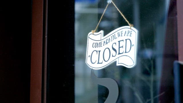 Closed sign hanging on a glass door