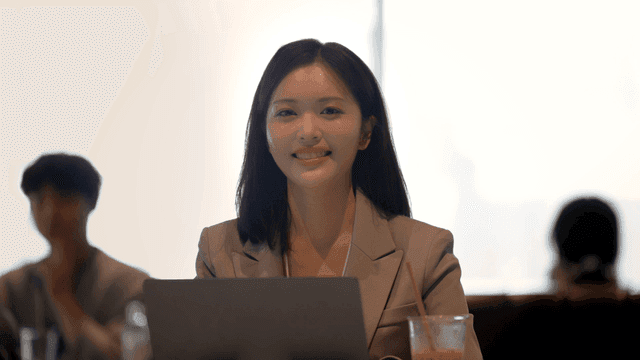 Female office worker smiling while looking straight ahead in cafe