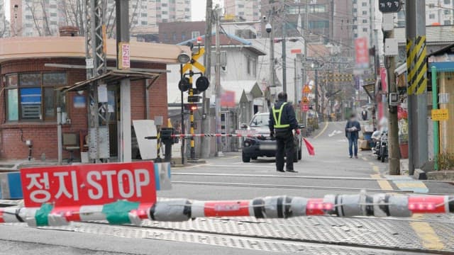 Stop sign at a Samgak Baekbin RC and pedestrians waiting for a train to pass