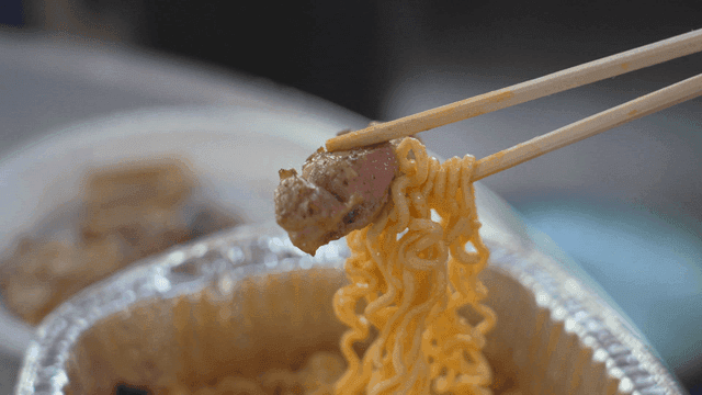 라면과 삼겹살을 집은 나무 젓가락