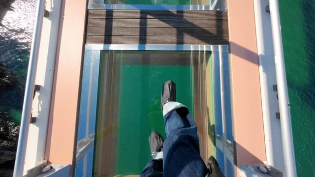 맑은 날 바다 위 스카이워크를 건너는 관광객들