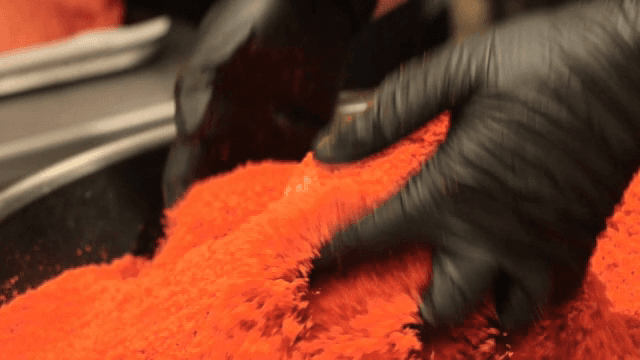 Hands putting red powder on bread