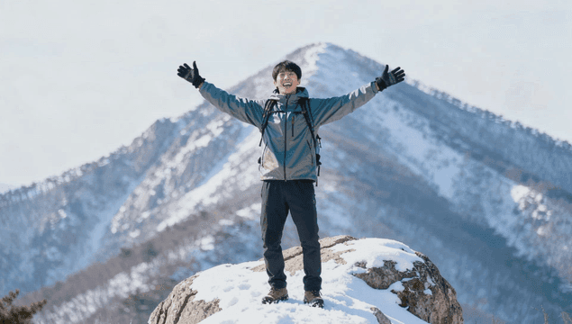 눈 덮인 산 정상에서 기뻐하는 남자