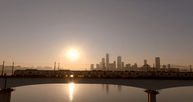 일몰 시간대에 강 위의 다리를 건너는 기차