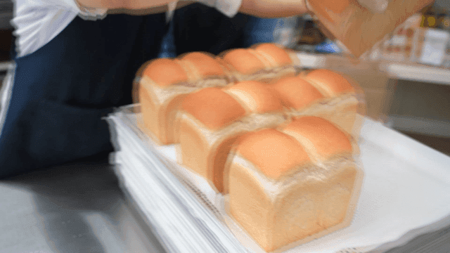 갓 구운 식빵들을 트레이에 옮기는 사람