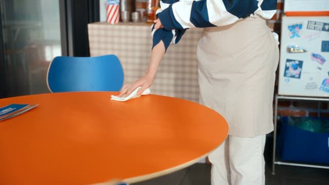 Woman cleaning a table in a pizza shop