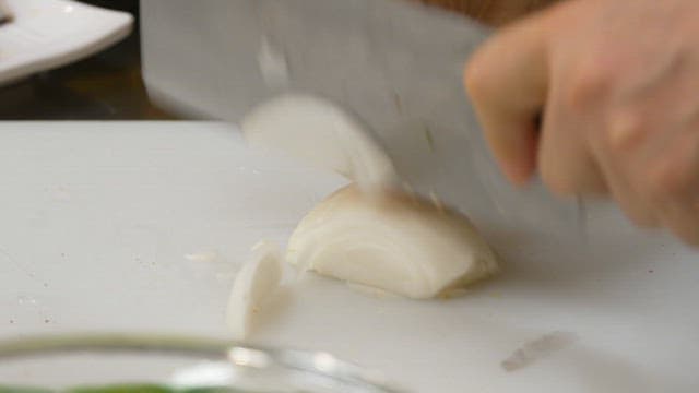 Slicing onions with a knife on a cutting board