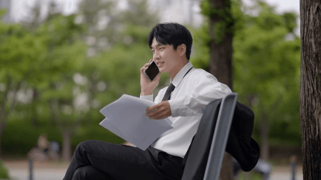 Office worker man reading documents and talking on the phone on a bench