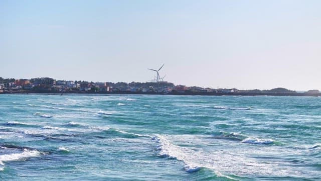 Coastal town with wind turbines and waves