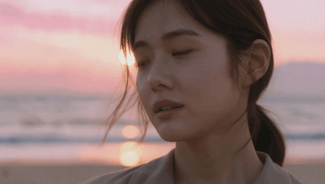 일몰 앞 해변에서 정면을 보는 젊은 여성